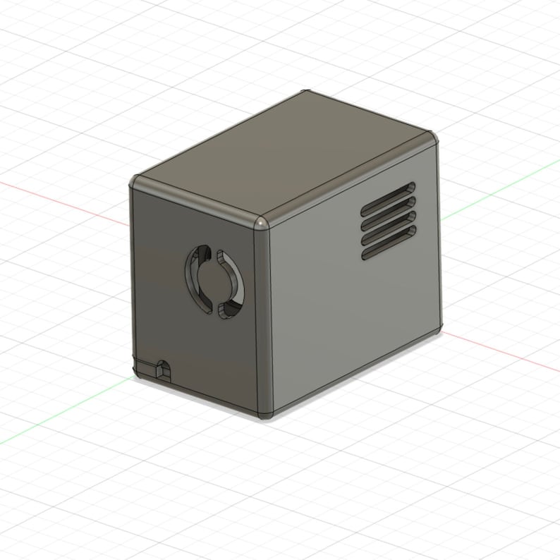 K&ouml;nnte beinhalten: Eine graue, rechteckige Box mit einem runden L&uuml;ftungsgitter an der Seite und einem rechteckigen L&uuml;ftungsgitter an der Oberseite. Die Box ist aus einem glatten, matten Material gefertigt.