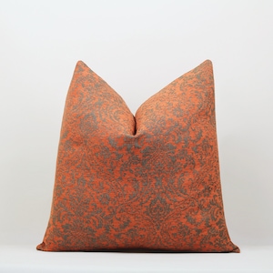 May include: A decorative throw pillow with a damask pattern in shades of orange and gray.