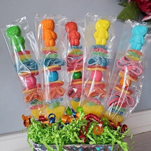 May include: A colorful candy bouquet with gummy candies and a variety of shapes in a silver gift box with green shredded paper and colorful ribbons.