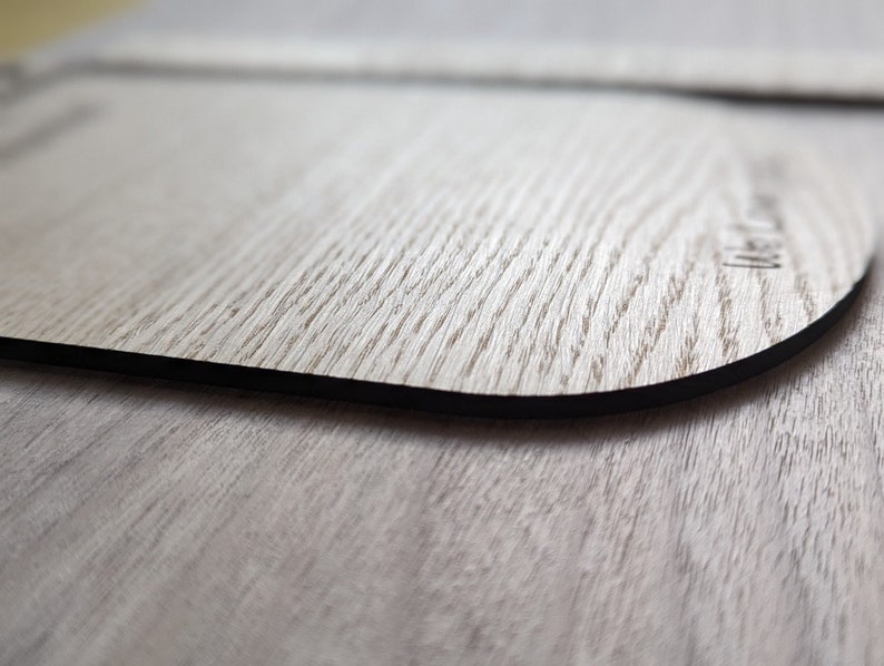K&ouml;nnte beinhalten: Ein Holz-Untersetzer mit schwarzem Rand. Der Untersetzer hat eine nat&uuml;rliche Holzmaserung und der Text "Made with Love" ist in die Oberfl&auml;che graviert.