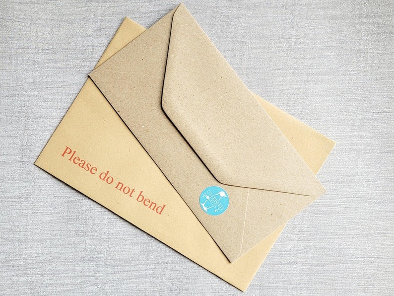 May include: A brown envelope with a "Please do not bend" label in red text. The envelope has a blue circular sticker with a white graphic.