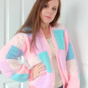 May include: A pastel pink, blue, and white crocheted cardigan with button closures.