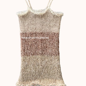 May include: A beige and brown knitted tank top with thin straps that tie at the shoulders. The tank top has a loose fit and a slightly ruffled hem.