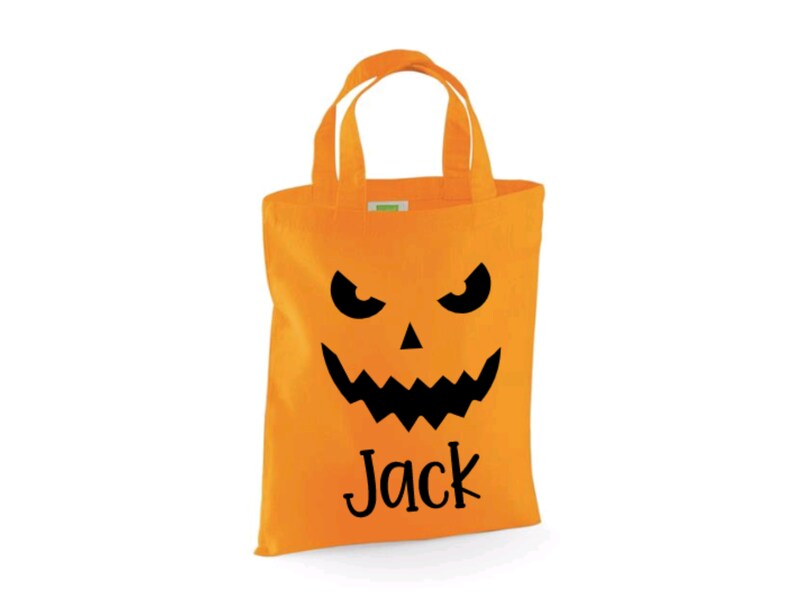 Puede incluir: Bolsa de truco o trato de Halloween naranja con una cara de calabaza negra y el nombre "Jack" impreso en la parte delantera.