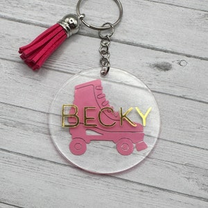 May include: Pink roller skate keyring with a gold name "BECKY" on a clear acrylic circle. The keyring has a pink tassel.