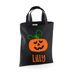 Puede incluir: Bolsa negra de truco o trato con una cara de calabaza verde y naranja y el nombre "Lilly" impreso en la parte delantera.