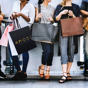 May include: Five people are holding shopping bags. The bags are various colors and sizes. One bag has the text "AMORE COLLECTION" printed on it.