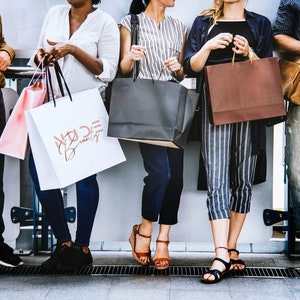 May include: Five people are holding shopping bags. The bags are various colors and sizes. One bag has the text "Wilde Beauty" printed on it.