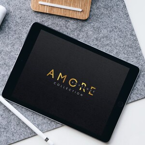 May include: A black tablet with a gold logo that says "AMORE BOUTIQUE COLLECTION" on the screen.