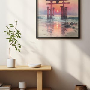 May include: Framed art print of a Japanese torii gate at sunset. The red gate stands in the water, with the sun setting behind it, creating a vibrant orange and pink sky. The print is in a black frame.