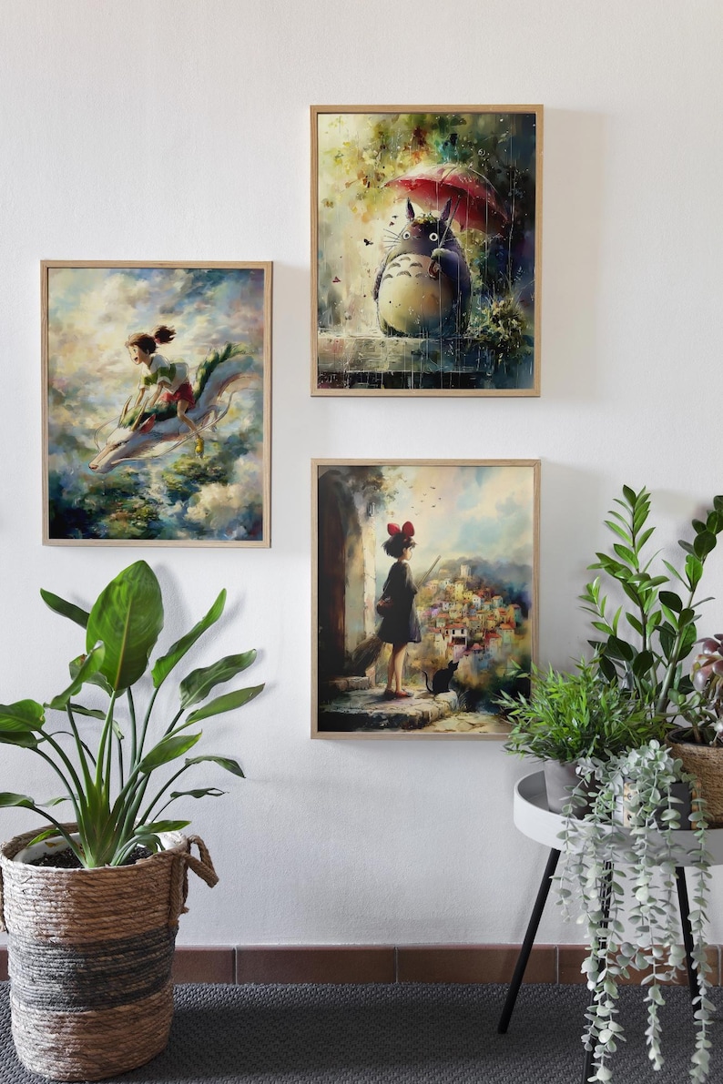 May include: Three framed art prints depicting scenes from animated films. One shows a girl riding a dragon, another a large, furry creature under a red umbrella, and the third a girl looking at a town.