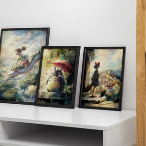 K&ouml;nnte beinhalten: Drei gerahmte Kunstdrucke mit Szenen aus Zeichentrickfilmen. Die Drucke zeigen ein M&auml;dchen, das auf einem Drachen reitet, Totoro unter einem Regenschirm und ein M&auml;dchen mit einer schwarzen Katze. Die Rahmen sind schwarz, und die Drucke werden auf einer wei&szlig;en Oberfl&auml;che pr&auml;sentiert.