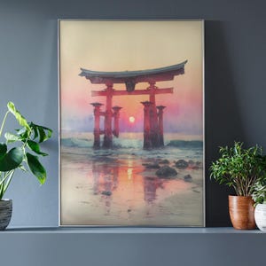 May include: Framed art print of a Japanese Torii gate at sunset. The red gate stands in the ocean, with the sun setting behind it, casting a warm glow. The artwork is displayed on a gray wall, with potted plants in front.