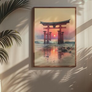 May include: A framed print of a Japanese torii gate at sunset. The artwork depicts the gate in the water with the sun setting behind it, creating a warm, orange and red color palette. The frame is a light brown color.