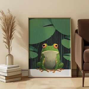 May include: A framed wall art print featuring a green frog with large orange eyes sitting in the rain. The background displays dark vertical lines representing rainfall and several large, rounded green lily pad leaves overhead.
