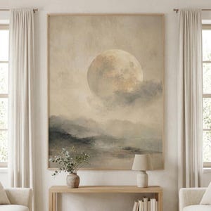 Könnte beinhalten: Ein rechteckiger Wandkunstdruck mit einem großen, blassen Mond, der teilweise von weichen, grauen Wolken über einer dunstigen, gedämpften Landschaft verdeckt wird. Das Kunstwerk ist in Beige-, Creme- und Anthrazittönen gehalten und hell gerahmt.