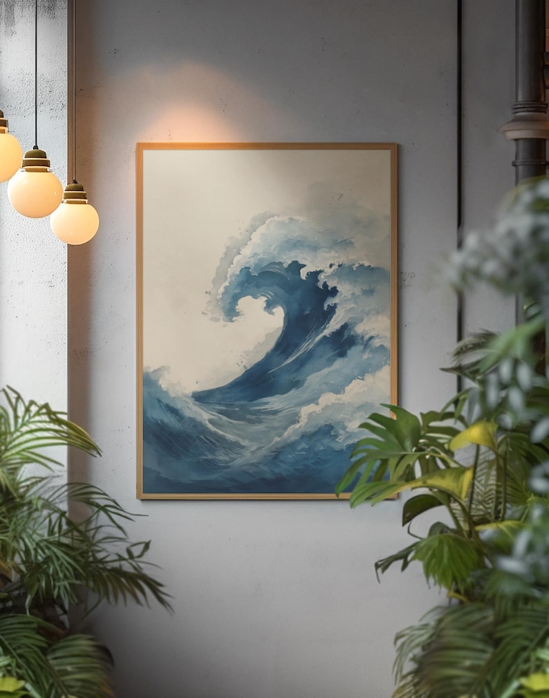 May include: A framed art print depicts a large ocean wave in shades of blue and white. The artwork is in a wooden frame and hangs on a gray wall. The image is surrounded by green plants and hanging light fixtures.