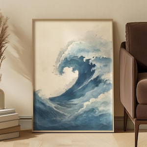 May include: A framed art print featuring a watercolor depiction of a large ocean wave. The wave is rendered in shades of blue and white, with a foamy crest and a sense of movement. The artwork is set against a neutral background.