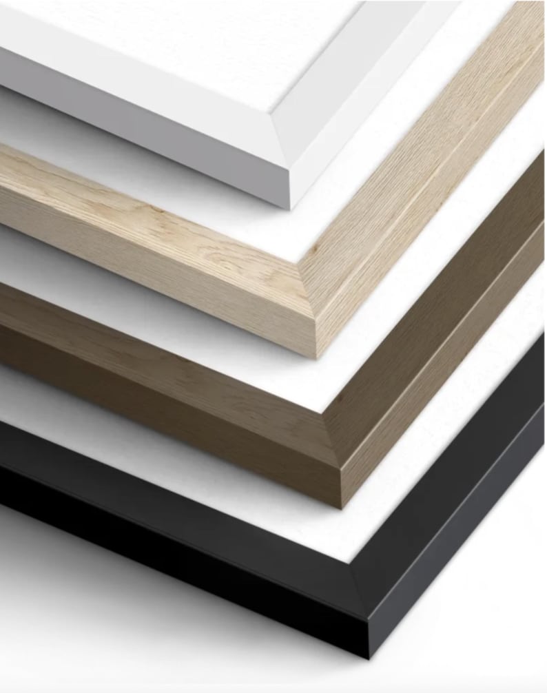 May include: A close-up view showcases a stack of picture frames in various colors. The frames include white, light wood, medium brown, and black. Each frame has a clean, modern design with a beveled edge, creating a layered effect.