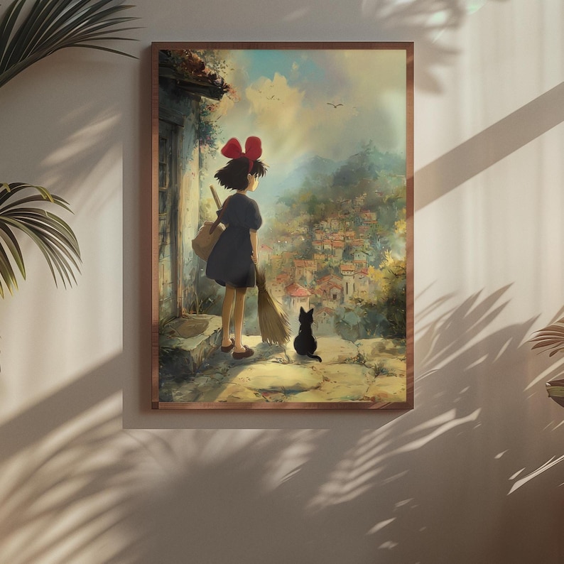 May include: A framed print featuring a young girl with a red bow, black dress, and a broom, standing with a black cat. The artwork depicts a village scene with a soft, painterly style, evoking a sense of fantasy and adventure.