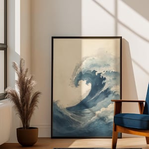 May include: A framed art print featuring a large, stylized wave in shades of blue and white. The artwork is displayed in a living room setting, with a blue chair, a decorative plant, and a blue rug.