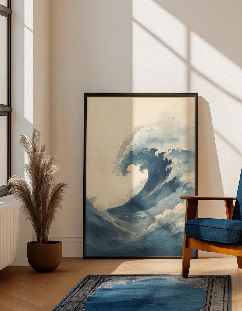 May include: A framed art print featuring a large, stylized wave in shades of blue and white. The artwork is displayed in a living room setting, with a blue chair, a decorative plant, and a blue rug.