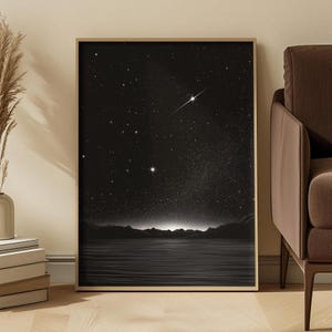 Puede incluir: Una lámina de arte mural rectangular enmarcada que muestra un cielo nocturno en blanco y negro sobre una masa de agua tranquila. La escena representa un horizonte oscuro con montañas silueteadas, un cielo estrellado y una estrella fugaz.