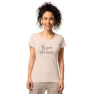 May include: A light pink women's t-shirt with a round graphic that says "Beyond Blessed" in black script.