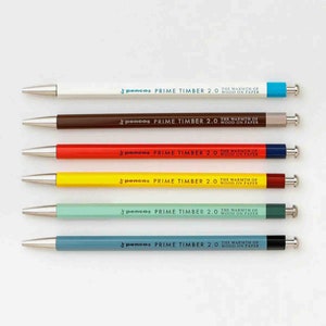Puede incluir: Seis bolígrafos con cuerpos de diferentes colores y detalles plateados. Cada bolígrafo tiene el texto "pencos PRIME TIMBER 2.0 THE WARMTH OF WOOD ON PAPER" impreso en el cuerpo.