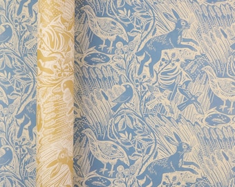 May include: A roll of wallpaper featuring a repeating pattern of hares and birds amidst wheat stalks and foliage. The design is rendered in a light blue and cream color palette, showcasing a detailed illustration of wildlife in a natural setting.
