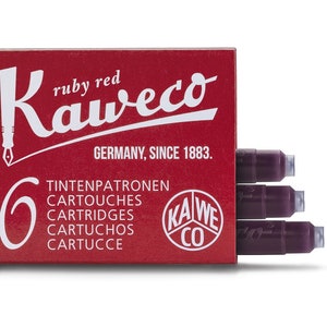 May include: A red box of Kaweco ruby red ink cartridges. The box has white text that reads "Kaweco" and "Germany, Since 1883." The box contains six cartridges. Three cartridges are visible, showing the dark red ink.