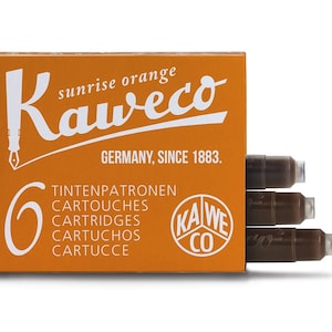 May include: Orange box of Kaweco sunrise orange ink cartridges. The box has the Kaweco logo and text that reads "GERMANY, SINCE 1883." The box contains six cartridges. Three cartridges are visible.