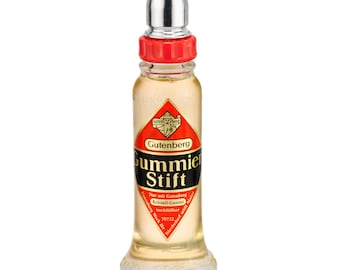 May include: A clear glass bottle with a red and gold label that reads "Gutenberg Gummie Stift". The bottle contains a clear liquid and has a silver cap.
