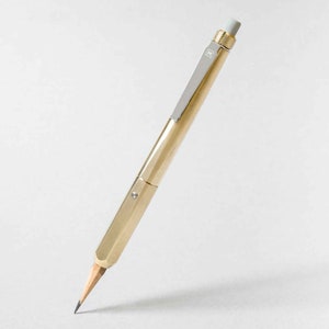 May include: A gold mechanical pencil with a silver eraser and a silver band with the letter "H" on it.