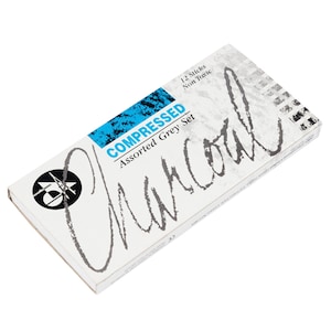 Puede incluir: Una caja blanca con texto azul que dice "COMPRESSED Assorted Grey Set Charcoal" y "12 Sticks Non Toxic".