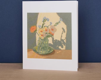 May include: A greeting card featuring a printed illustration of a clear glass jar filled with a small bouquet of orange, yellow, and blue flowers. The jar sits on a saucer, casting a distinct shadow against a muted green wall background.