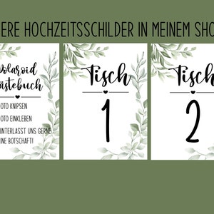 Pu&ograve; includere: Tre cartelli da matrimonio stampabili con un bordo di foglie verdi. Il primo cartello dice "Polaroid Guestbook" con istruzioni per scattare una foto, incollarla e lasciare un messaggio. Il secondo e il terzo cartello dicono "Tisch" (tedesco per "Tavolo") con i numeri 1 e 2.