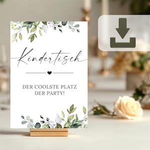 May include: A white card with green and white floral illustrations and black text that reads "Kindertisch Der Coolste Platz Der Party!" The card is on a gold stand.