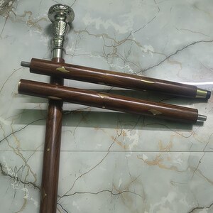 May include: A wooden walking cane with a silver-colored handle and decorative brass accents. The cane is brown with a dark finish and has a screw-on design for easy assembly. The cane measures approximately 36 inches in length.