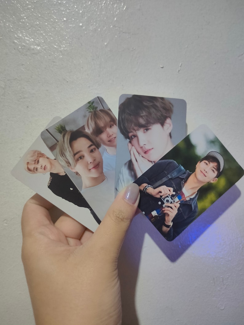 May include: A collection of four rectangular photo cards featuring portraits of various individuals. One card shows a person with a camera, while the others display close-up headshots of different people with light-colored hair and neutral expressions.