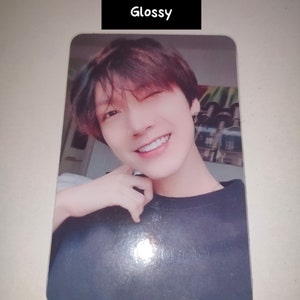 May include: A rectangular glossy photo card featuring a portrait of a person with dark hair, winking and smiling. The person wears a dark-colored shirt. Above the portrait, a black rectangular label contains the white text "Glossy".