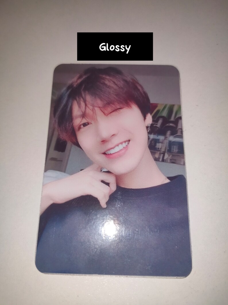May include: A rectangular glossy photo card featuring a portrait of a person with dark hair, winking and smiling. The person wears a dark-colored shirt. Above the portrait, a black rectangular label contains the white text "Glossy".