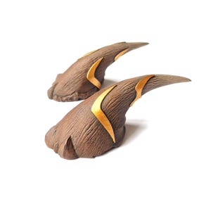 May include: Two brown, claw-like props with gold accents. The claws are pointed and have a textured surface.