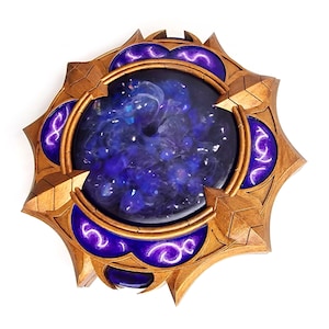 Könnte beinhalten: Ein dekoratives, sternförmiges Objekt mit einem zentralen, kreisförmigen, tiefblauen Design. Das Objekt hat einen goldfarbenen Rahmen mit lila Akzenten. Das zentrale Design scheint ein nebelartiges Muster zu haben. Das Gesamtdesign ist aufwendig und detailliert.