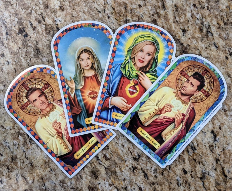 May include: Four colorful illustrated cards with a religious theme. Each card features a different person with a halo and a name at the bottom. The cards are decorated with gold accents and floral patterns.