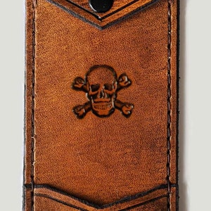 May include: A brown leather wallet with a skull and crossbones design and the initials "E.G." embossed on the front.