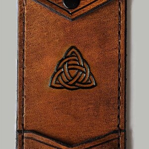 May include: A brown leather wallet with a Celtic knot design and the initials "E.G." embossed on the front.