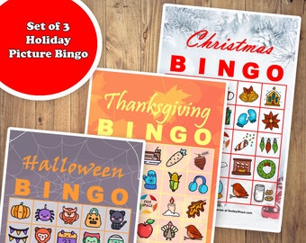 May include: Set of 3 holiday picture bingo games. The games include Halloween, Thanksgiving, and Christmas themes. Each bingo card features colorful illustrations and the word "BINGO" in large letters. The background is a wooden surface.