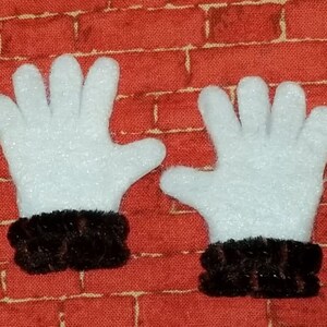 May include: A pair of white felt gloves with black felt cuffs. The gloves are on a red brick background.