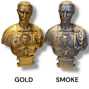 May include: Two bust sculptures of a Roman emperor, one in gold and one in smoke finish. Both sculptures feature detailed armor and a fierce expression.
